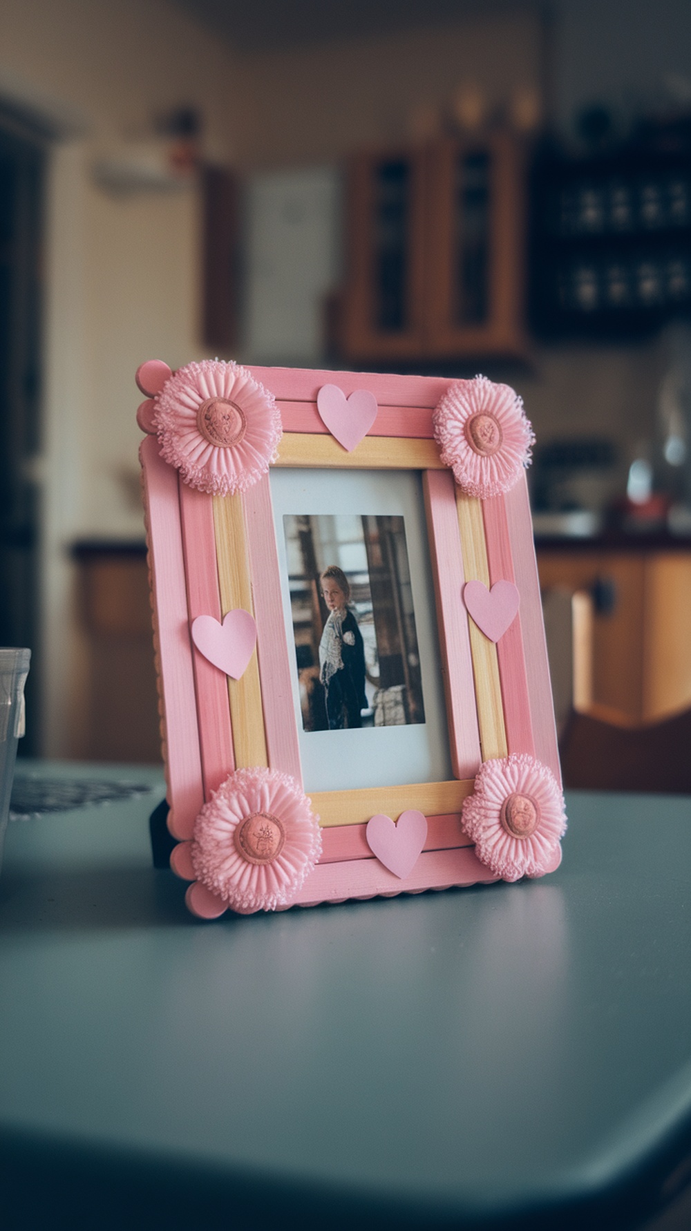 Colorful popsicle stick photo frame decorated with embellishments, displaying a photo inside